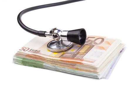 Black stethoscope  on pile of euro banknotes closeup isolated on white backgroundの写真素材