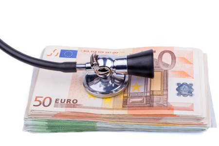 Black stethoscope  on pile of euro banknotes closeup isolated on white backgroundの写真素材