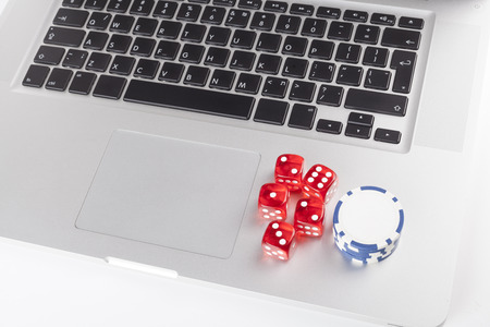 Red casino dices with chips on silver laptopの写真素材