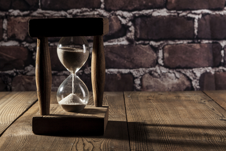 Beautiful hourglass on brown wood table with shadow