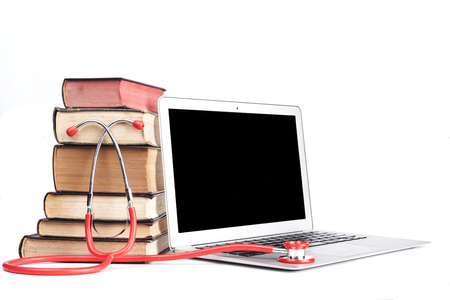 Silver laptop with red stethoscope and old pooks pile isolated on white backgroundの写真素材