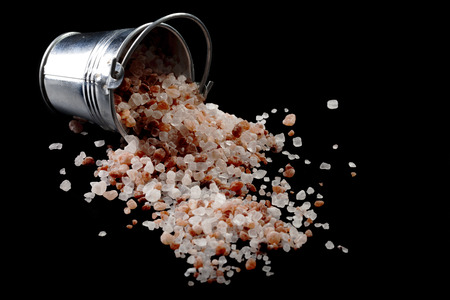 Spilled Himalayan Salt From Silver Metal Bucket on Black Backgroundの写真素材