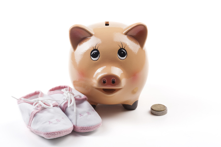 Piggy Bank With Newborn Baby Girl Shoes With Some Coins Isolated on White Backgroundの写真素材