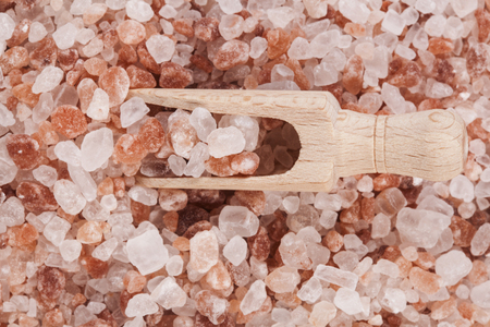 Himalayan Salt Raw Crystals Pile with Brown Wood Spice Scoop Isolated on White Backgroundの写真素材