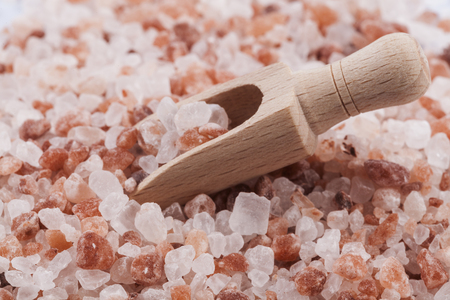 Himalayan Salt Raw Crystals Pile with Brown Wood Spice Scoop Isolated on White Backgroundの写真素材