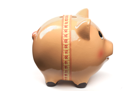 Cute Piggy Bank With Yellow Measuring Tape Isolated on White Backgroundの写真素材