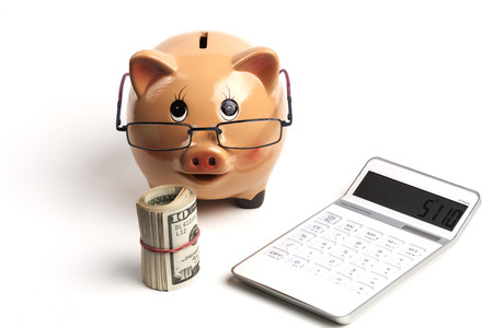 Piggy Bank With Dollars Roll and Calculator Isolated on White Backgroundの写真素材