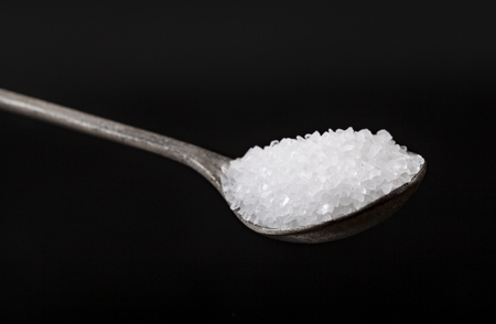 Silver Spoon Full With White Salt Crystals On Black Backgroundの写真素材