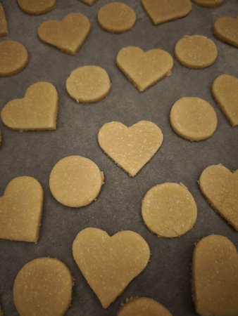 Preparing heart and circle shaped cookies on a baking sheet covered with parchment paper for...