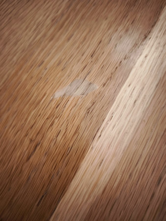 Close up of a spot without varnish on the table stain blemishing oak wood grain, highlighting the need for furniture repair or restorationの写真素材