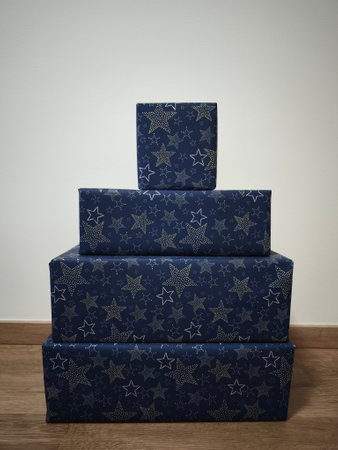 Four christmas gifts wrapped in blue wrapping paper with silver stars stacked to form a pyramid...