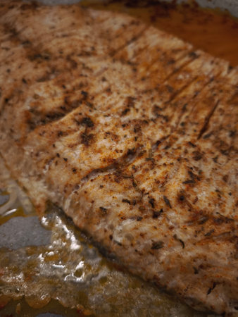 Seasoned fish fillet baking on parchment paper, prepared for a Christmas dinner in Prague, Czechia