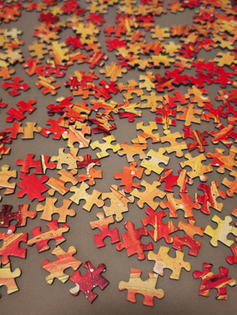 Puzzle pieces in warm orange and red tones scattered on a surface, evoking christmas anticipationの写真素材
