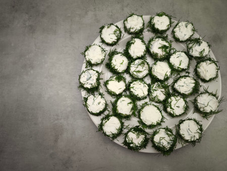 Delicious christmas appetizer featuring cucumber slices topped with cream cheese and fresh dill, prepared in Prague, Czech party food for aperitif, New Year's Eve dinner, Christmas or birthdayの写真素材