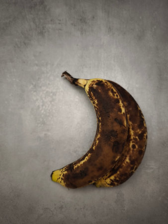 Two brown, overripe bananas lie on a gray countertop, showcasing their advanced stage of ripeningの写真素材