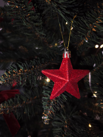 Red glittery star shaped christmas ornament hanging on a christmas tree, spreading holiday cheerの写真素材