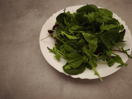 Fresh, vibrant green salad mix on a white plate, promoting healthy eating habits and vegetarian lifestyle. High quality photoの写真素材