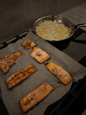 Delicious salmon fillets baking on a tray with a side of rice and corn in stainless steel frying pan. High quality photoの写真素材