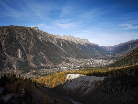 Scenic autumnal view of chamonix valley, featuring vibrant larch trees and imposing mountains under...