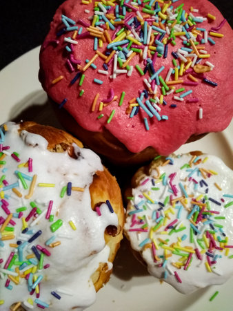 Three Easter cakes bread Kulich decorated with colorful sprinkles sitting on ceramic plate,...