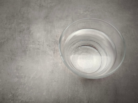 Clear drinking water sits in a glass placed on a gray concrete surface, promoting hydration and well being copy spaceの写真素材