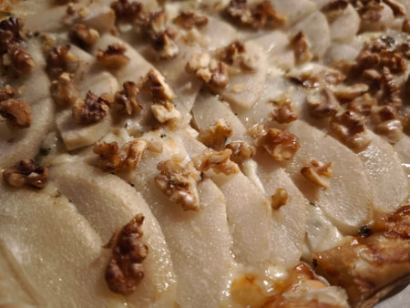 Close up of a pear and walnut tart with melted cheese, fresh from the oven, showing the inviting texture and flavorsの写真素材