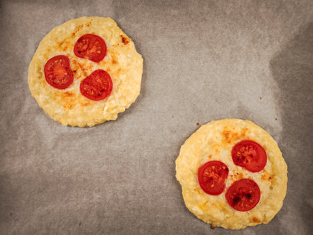 Mini pizzas topped with tomatoes and melting cheese, resting on parchment paper for valentine's breakfastの写真素材