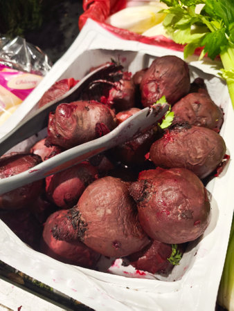 Fresh beets arranged on wooden display, metal tongs nearby, highlighting rustic market style produce...