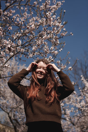 Teenager touching almond tree flowers in petrin gardens, prague, during springtime
