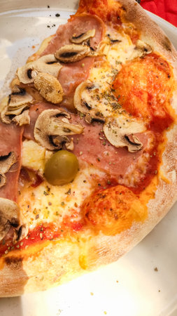 Close up of a pizza slice featuring ham, mushrooms, and melted cheese, savored during a croatian summer vacationの写真素材