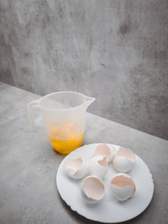 Eggs ready for baking, in a measuring jug and eggshells on a plate