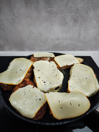 Cheese slices melting on top of toasted bread in a frying pan, creating a cheesy and comforting meal for breakfastの写真素材