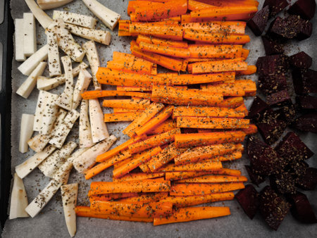 Colorful root vegetables seasoned with dried herbs, arranged on a baking sheet, prepared for roasting in the oven healthy dinner snacksの写真素材