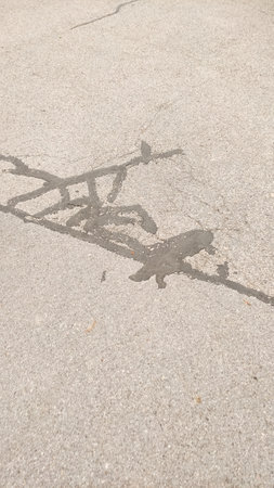 Cracks and patches marring a paved surface highlight the need for road maintenance in Czech Republic in Cesky Krumlovの写真素材