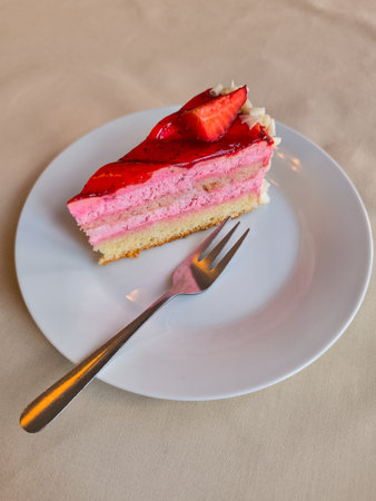 Enjoying a slice of strawberry cake with a fork on a white plate in a Prague restaurant, perfect for a sweet treat during a spring trip copy spaceの写真素材