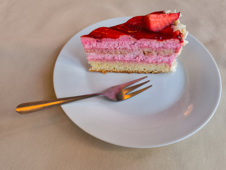 Slicing into a delectable strawberry cake on a white plate, savoring the sweet treat in a cozy Prague cafe during April copy spaceの写真素材