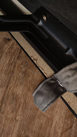Close up of damaged laminate flooring underneath a sofa, highlighting the impact of furniture on...