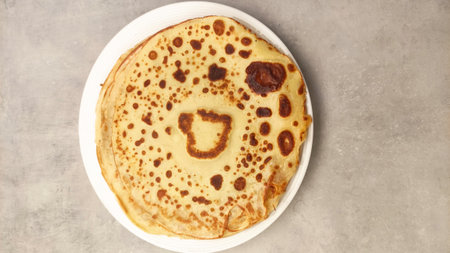 Warm, golden pancake featuring a charming heart design, placed on a clean white plate, inviting...