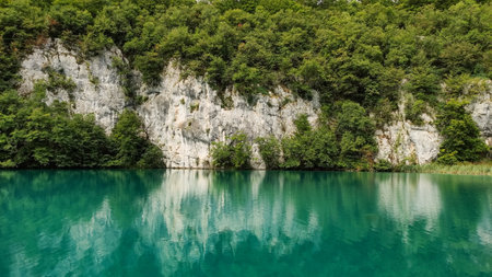 Calm turquoise lake reflecting the surrounding lush green forest and white cliffs in plitvice lakes national park, croatia, a unesco world heritage siteの写真素材