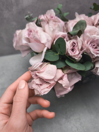 Florist gently touching a pink rose in a bridal bouquet, adding a touch of elegance to a wedding...