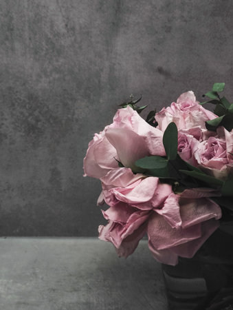 Wilting pink roses bridal bouquet with eucalyptus leaves on a dark background, conveying a sense of melancholy and lost loveの写真素材