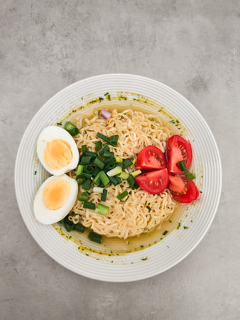 Enjoying a quick and delicious meal of instant noodles garnished with boiled eggs, fresh tomatoes,...