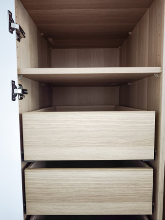 Modern wooden cabinet interior features empty drawers and shelves, highlighting a minimalist approach to design and organization for storage solutionsの写真素材