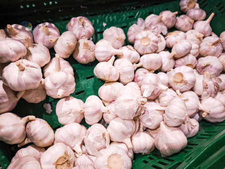 Fresh garlic bulbs arranged in a green basket display their unique texture and color, ideal for various culinary applications and healthy eatingの写真素材