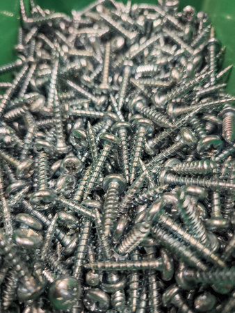 Close up view of numerous metal screws filling a green container, ready for various construction or do it yourself projectsの写真素材