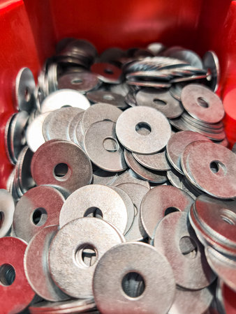 Close up of numerous metal washers filling a red container, showing essential hardware for construction and diy projectsの写真素材