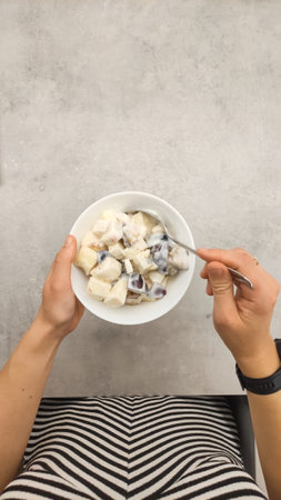 Woman enjoying a healthy breakfast or snack of fresh fruit salad with yogurt, promoting a healthy lifestyle copy spaceの写真素材