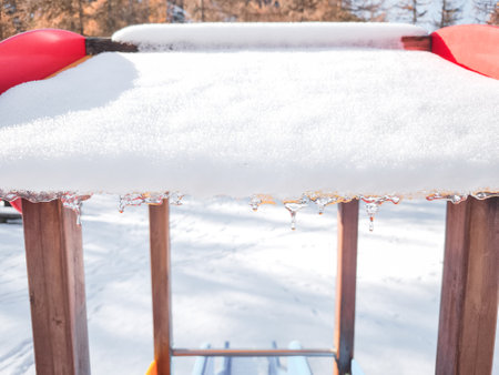 Snow covered playground structure with icicles melting under the sun in aosta, italy, capturing the serene beauty of winter in november Frazionne Lillazの写真素材