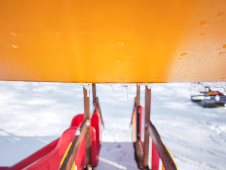 Icicles hang from a colorful playground slide in Aosta, Italy, contrasting with the snowy landscape of a November day Frazionne Lillazの写真素材