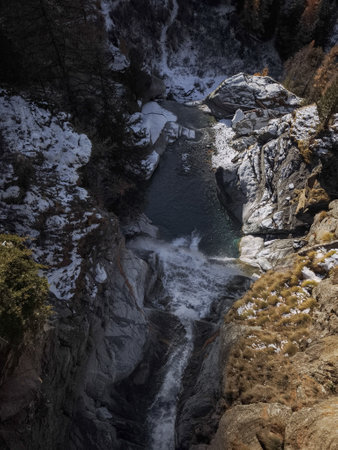 Capturing the serene beauty of a waterfall in aosta, italy, surrounded by rocky cliffs and snow...